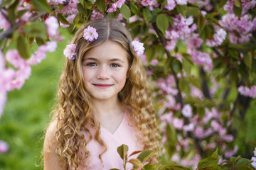 Beautiful little girl in blossom cherry garden on beautiful spring day	