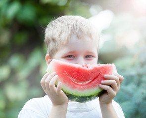 Boy smiling and eating watermelon
