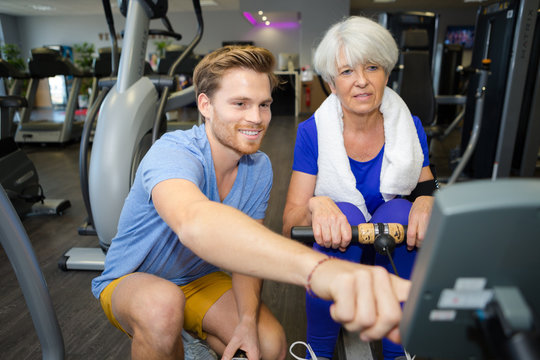 old happy woman exercising on rowing machine in gym