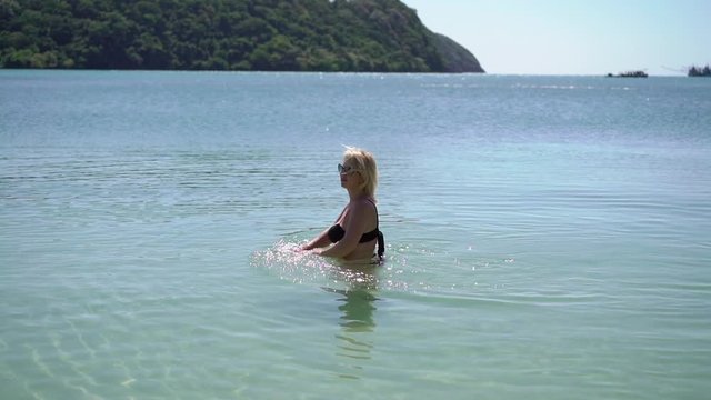 Young woman in black bikini in a sea at the beach