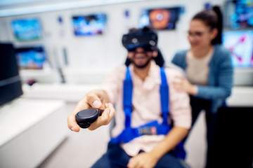 Fototapeta na wymiar Multiracial couple having fun with VR goggles while boy sitting in the chair in the tech store. Customer's service. Shopping time.