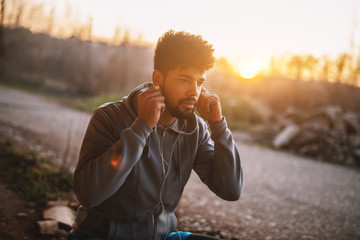 Portrait of focused motivated afro-american young handsome sportive man with earphones standing...