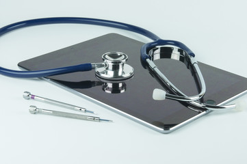 Stethoscope, tablet and screwdrivers.