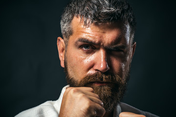 Male shows judo or karate in white kimono. Individual martial art sport. Sportsman martial art taekwondo training, in karate position. Muscular kickboxer or muay thai fighter.