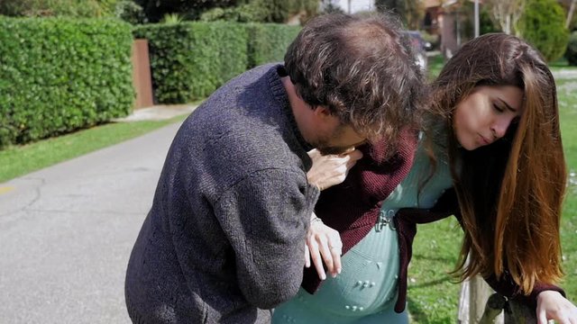 Man trying to help pregnant woman with contractions enter car slow motion