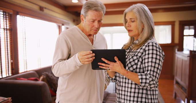 Charming mature couple looking at tablet computer