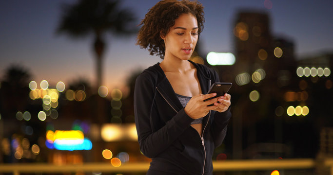 Lovely black woman using smartphone in urban setting