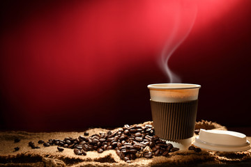 Paper cup of coffee with smoke and coffee beans on reddish brown background