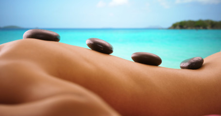 Close up portrait of woman have hot stone massage on caribbean beach