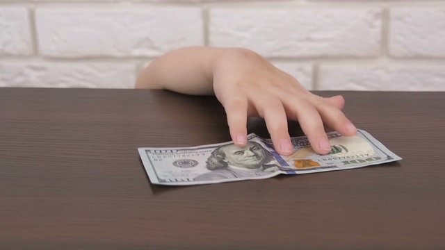 The child takes the money. The hand of the child stealing money from the table.