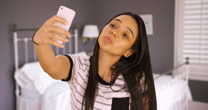 A Cute Teen Takes A Selfie In Her Bedroom With The Duck Face. A Young Girl Takes A Picture Of Herself With Her Smart Phone