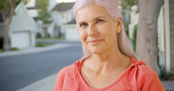 An Older Woman In Her Suburban Neighborhood. An Elderly Woman Standing Outside Of Her House