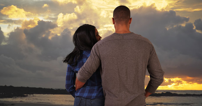 African American couple holding hands looking at beautiful sunset. Beautiful young happy couple in love on vacation in Costa Rica