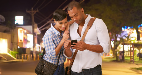 A African American couple calls a taxi while on a white background. A black boyfriend and girlfriend wait for their ride on a blank backdrop