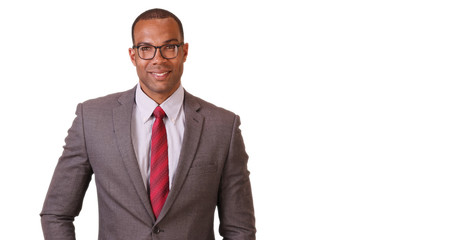 A black businessman poses for a portrait on a white background. An African American executive in a suit and tie stands looking at the camera on a blank backdrop