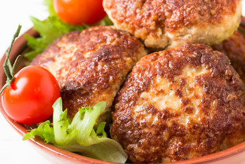 Homemade cutlets, tomatoes and lettuce on a plate.
