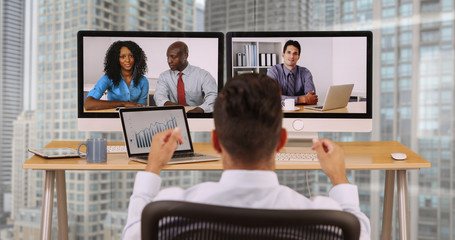 Hispanic business man in high rise corporate office having internet video conference with diverse...
