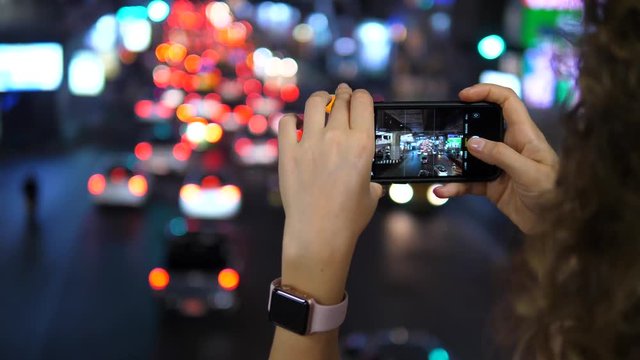 Woman Taking Photos Of Night Traffic Jam With Smartphone