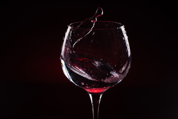 Red wine splashing out of a tall wine glass
