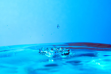 drop of water falling in blue water and blue background.