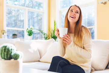 Happy young woman drinking coffee at home