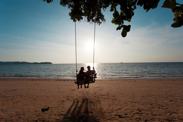 couple in love on a swing under a tree on the beach for relax 