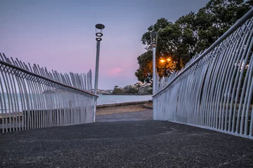 Foto auf Acrylglas Antireflex View of Mission Bay Beach at Sunset through an Artistic Walking Bridge © agcreationsnz