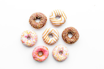 Donuts decorated icing and sprinkles on white background top view copy space pattern