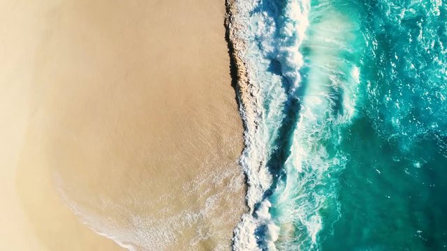 Aerial view waves break on white sand beach. Sea waves on the beautiful beach. drone 4k shot. zoom in