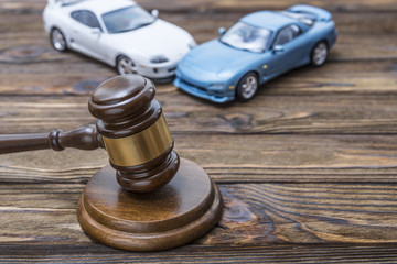 hammer of the judge. two collided cars on a wooden background.