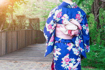 Naklejka premium Woman wearing Kimono traditional Japan walking on wooden bridge at park.