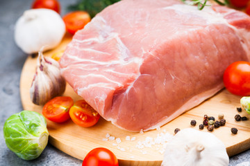 Raw pork on cutting board and vegetables 