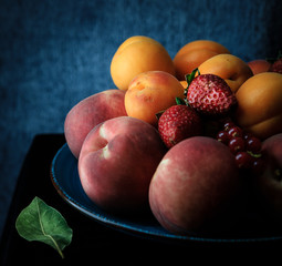fruit assortment in dark moody setting (strawberries, apricot and peach)
