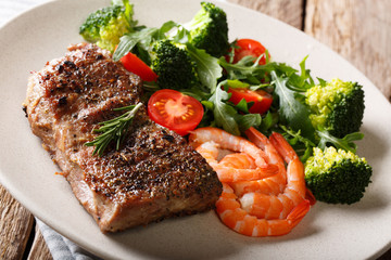 Beef steak with prawns and broccoli, tomatoes, arugula closeup on plate. Horizontal.  Surf and Turf