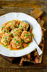 Meatballs stewed with tomato sauce in a plate on a wooden table