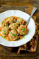 Meatballs stewed with tomato sauce in a plate on a wooden table