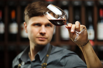 Bokal of red wine on background, male sommelier appreciating drink
