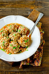 Meatballs stewed with tomato sauce in a plate on a wooden table