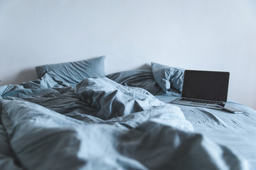 empty messy grey bed with laptop. lifestyle rest in bed concept - obrazy, fototapety, plakaty