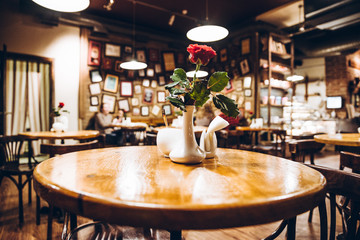 cafe inside. empty table with red rose in vase