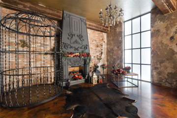Interior with fireplace, candles, skin of cows, brick wall, large window and a metal cell of a loft, living room, coffee table in modern design