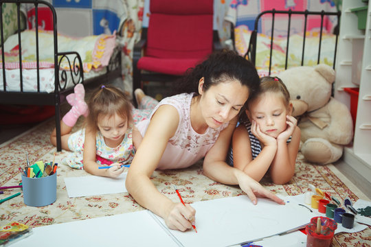 Mom and daughters painting pictures and lying on floor