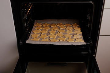 the process of making christmas cookies, raw dough, rolling pin and baking star forms.