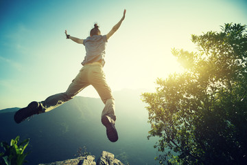 hipster woman hiker jumping on cliff's edge