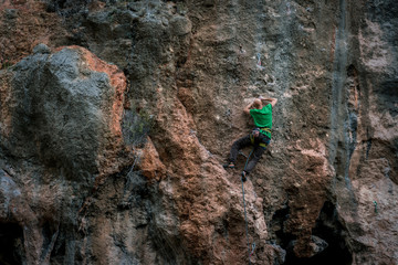 bald man climbs rock, side view, Turkey