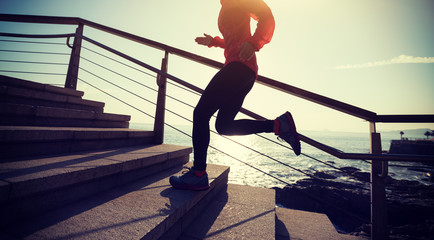 sporty female runner running upstairs on coast trail