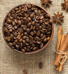 Cinnamon, star anise and coffee beans in a barrel on a burlap napkin. Top view