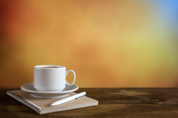 White coffee cup and notepad on colorful background. With copy space