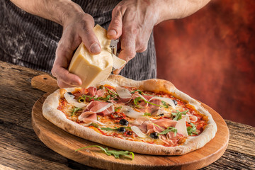 Pizza and Chef. Chef in the restaurant prepares a pizza and decorates it with parmesan cheese