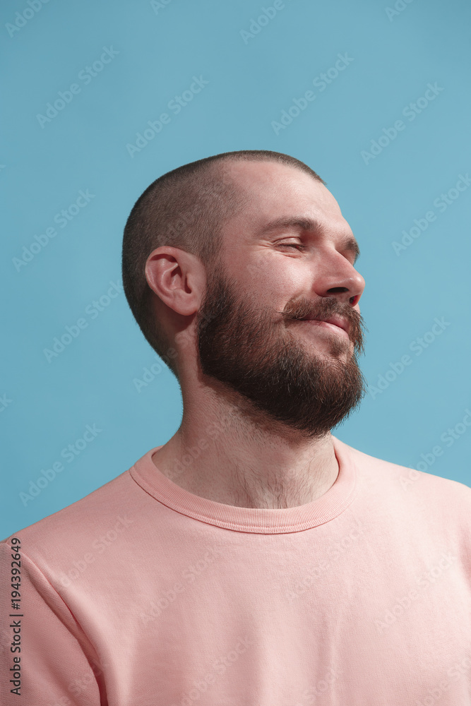 Wall mural isolated on blue young casual man smiling and enjoying at studio